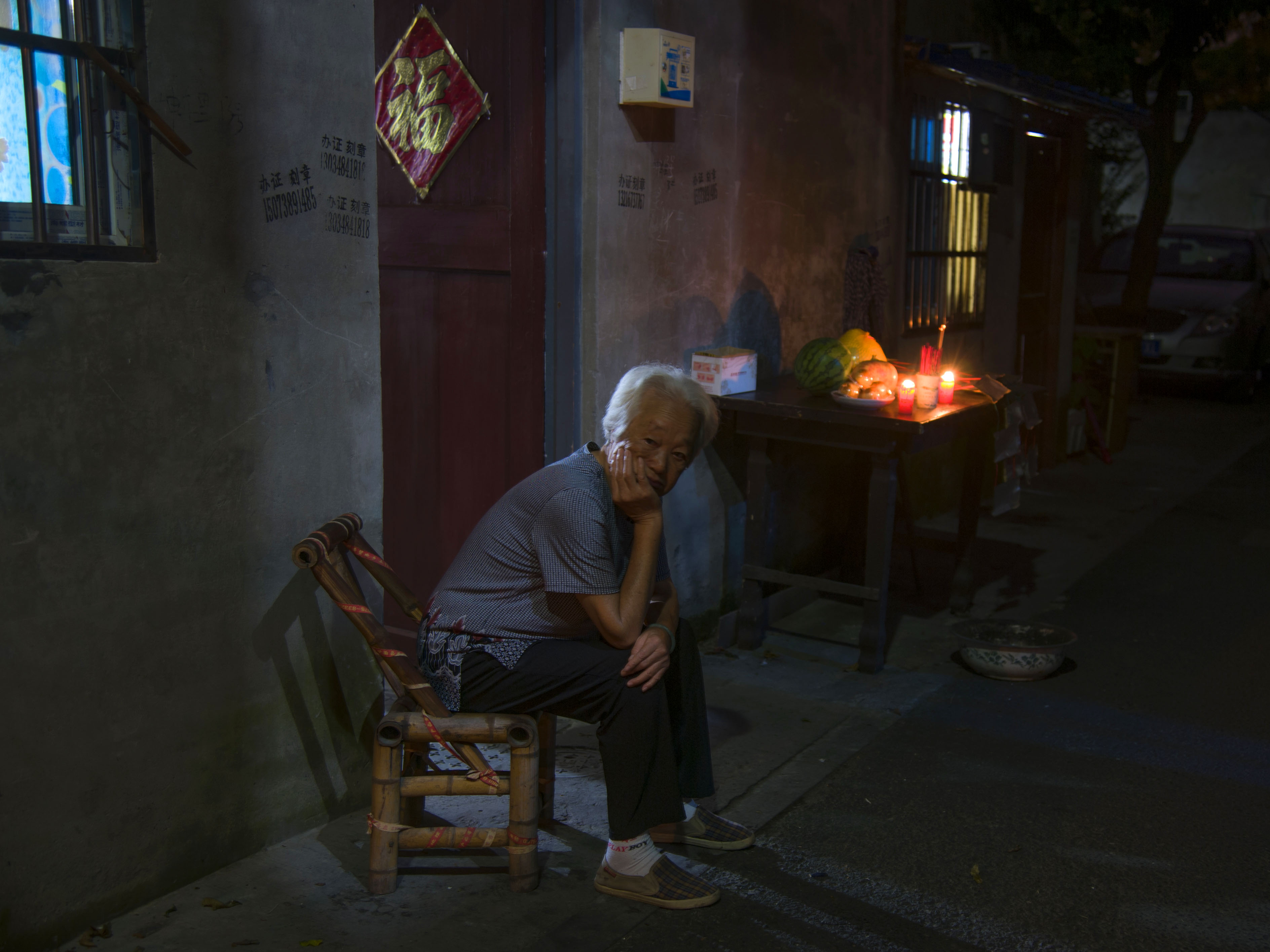 中秋佳节,老人在家门口,点上蜡烛,摆上贡品,思念远方的家人.